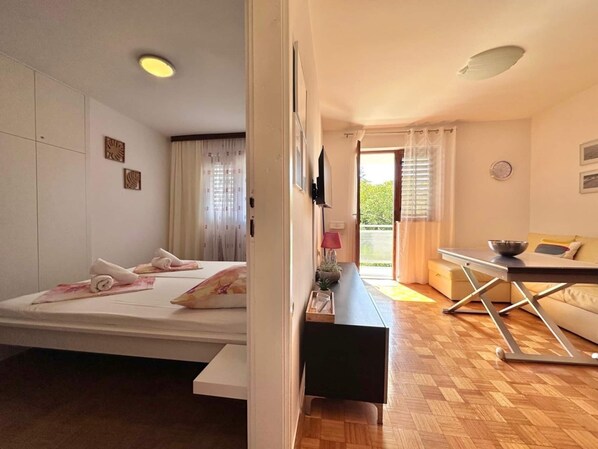A modern bedroom with a bed, bedside table, and a view of the outdoors.