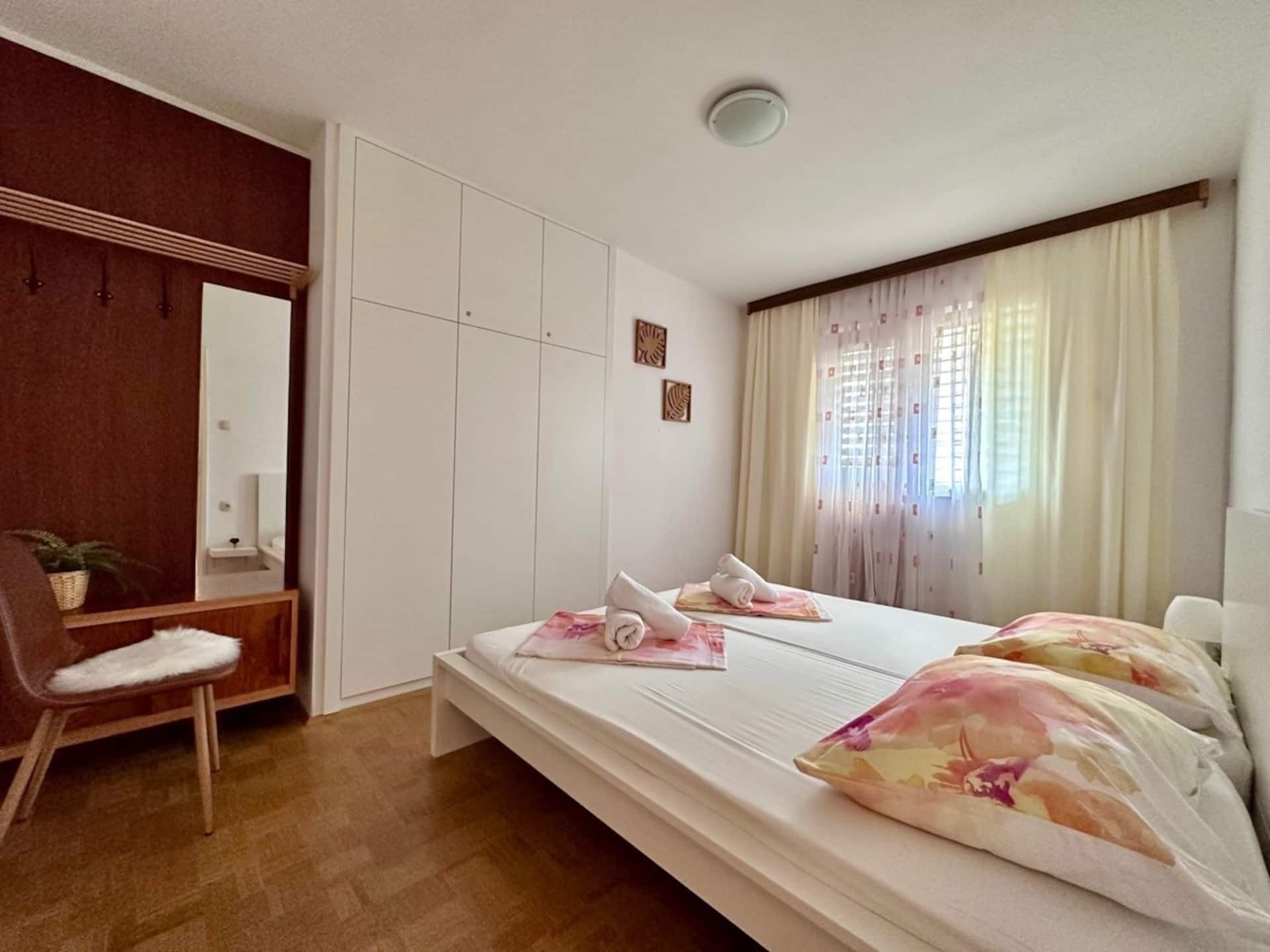 A bedroom with a bed, a chair, a wardrobe, and a mirror.
