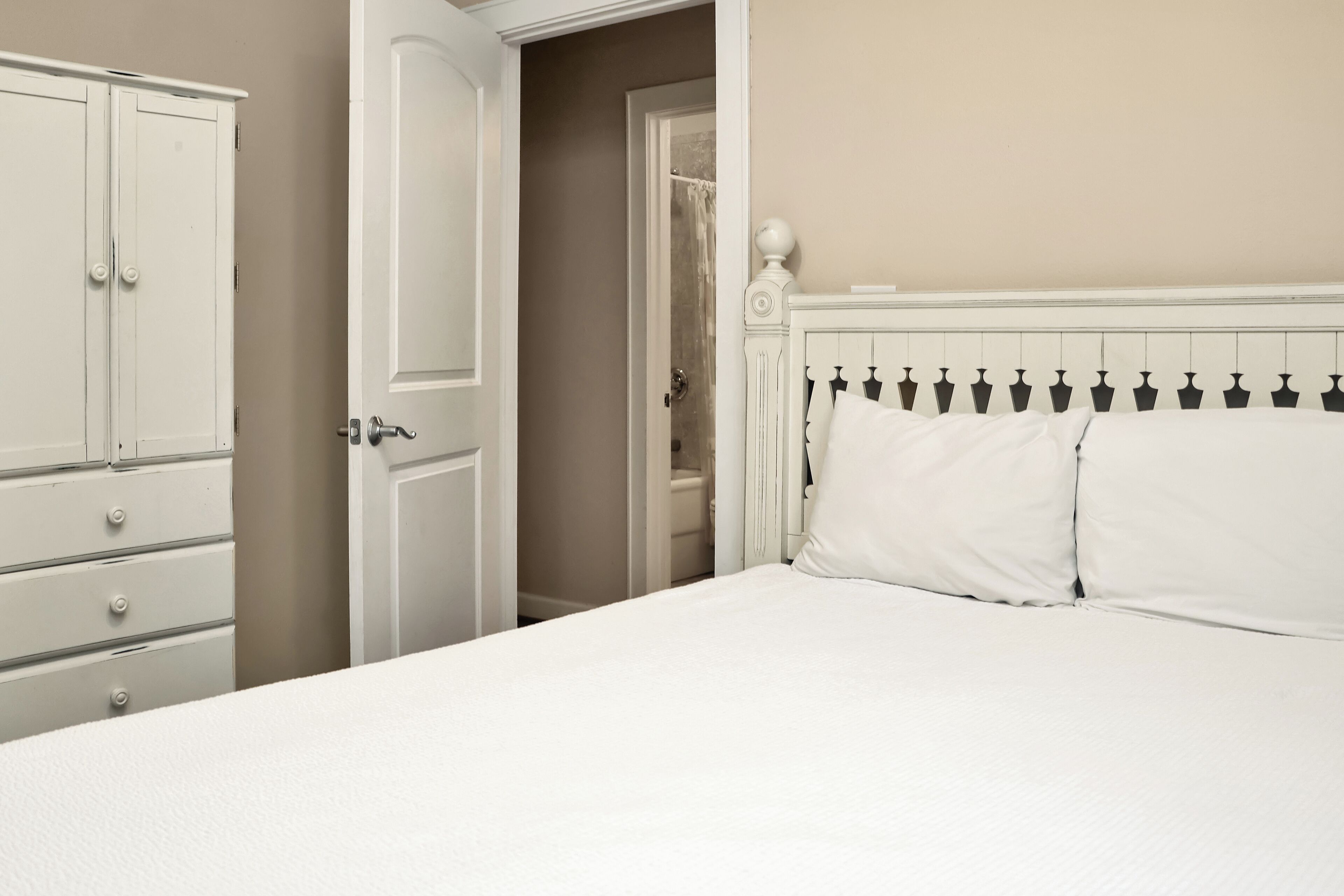 Un dormitorio con cama, armario y puerta que da a un baño.