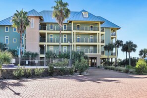 Stunning hotel with a central entrance, flanked by palm trees, and a flat roof with balconies on each floor.