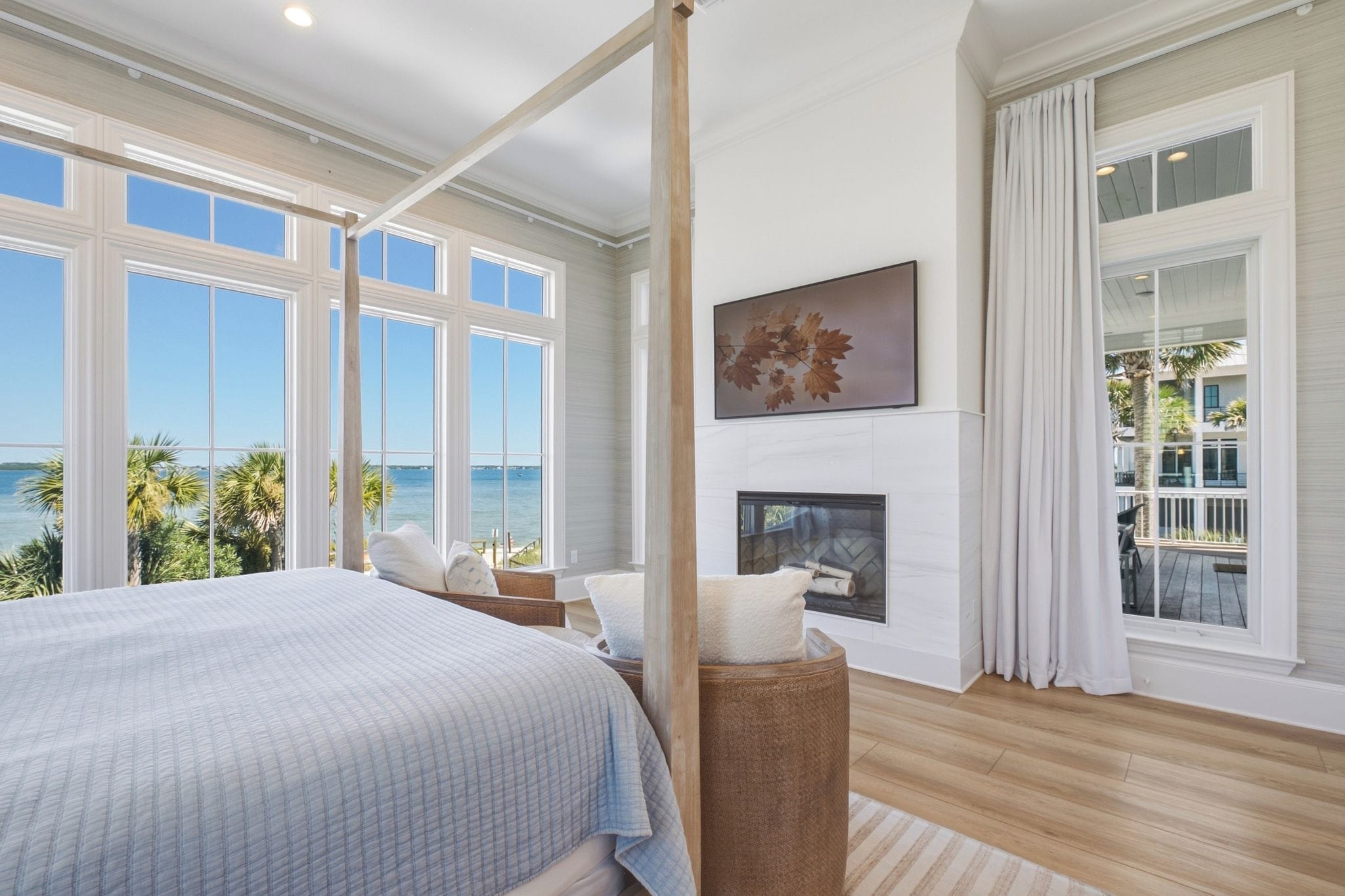A bedroom with a large bed, a fireplace, and a view of the ocean.