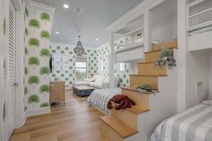A bedroom with a bunk bed, a staircase, and a large window.