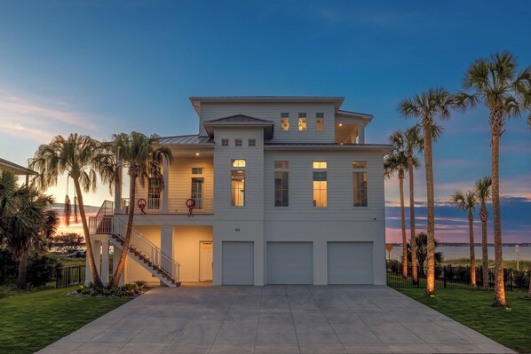 A two-story waterfront house with a balcony, a garage, and a well-maintained lawn.