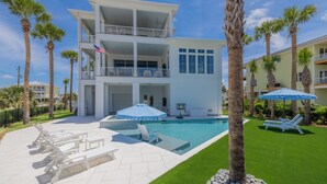 A two-story house with a swimming pool, outdoor seating, and palm trees. - Luxury Sound-View Escape with Private Pool, Hot Tub, and Stunning Amenities! (Pensacola Beach)