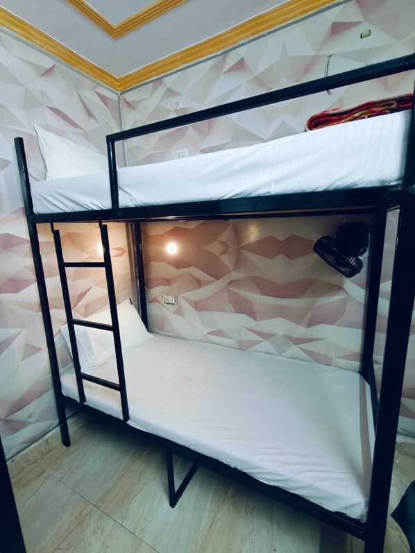 Una cama litera con una escalera, un estante pequeño y una pared con un diseño geométrico.