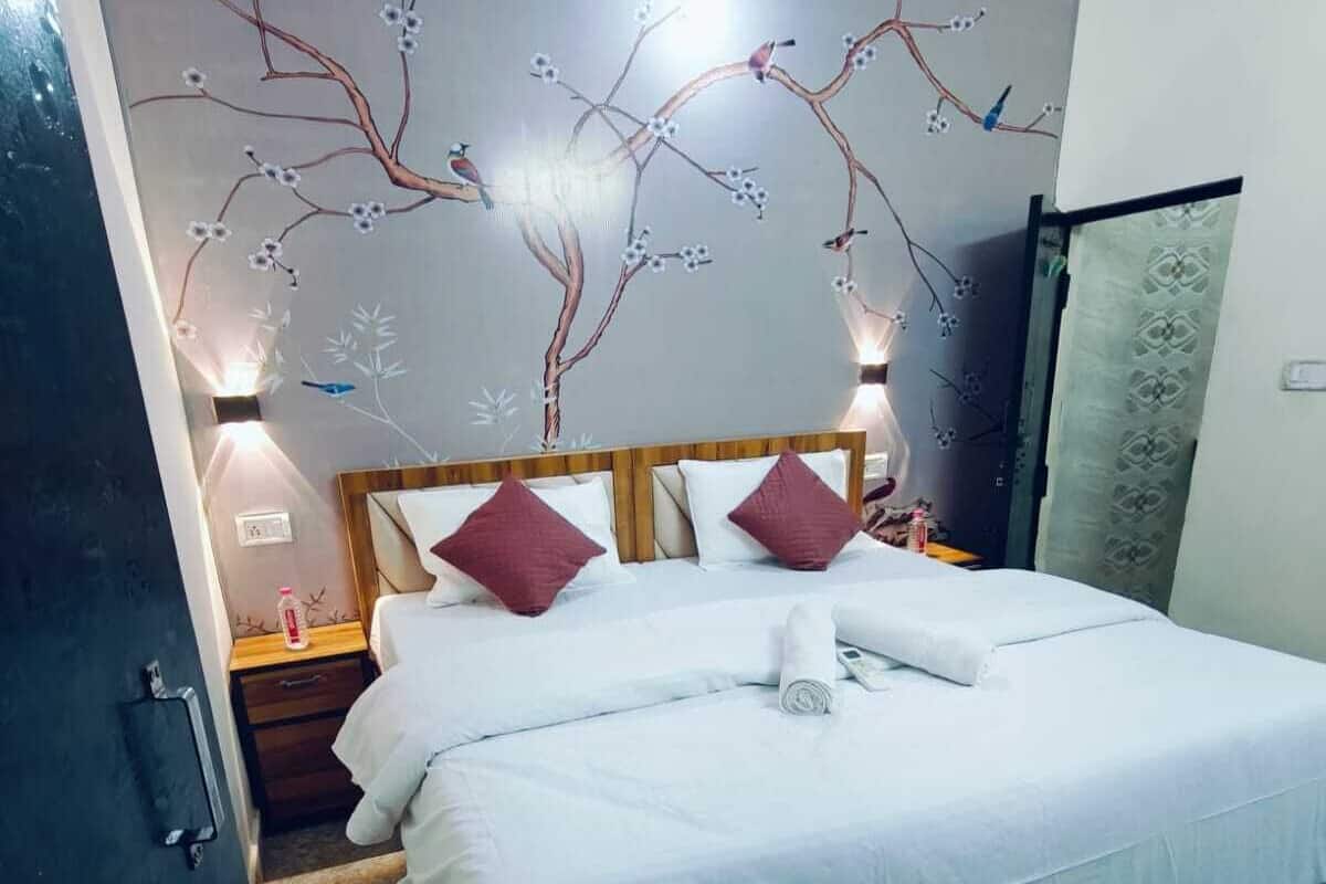 Une chambre d’hôtel avec un lit, une table de chevet, une fresque murale et une porte.