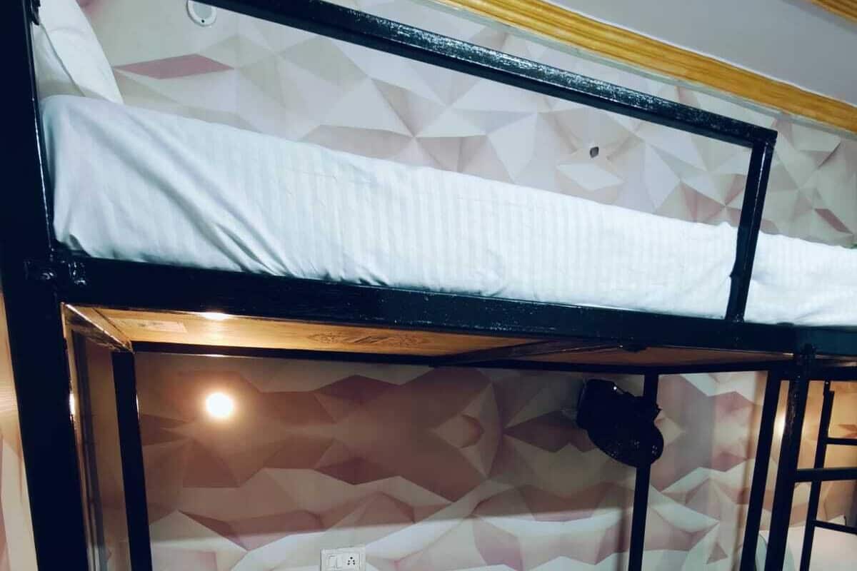 Un lit superposé avec un mur orné d’un motif géométrique et une prise de courant sur le lit du bas.