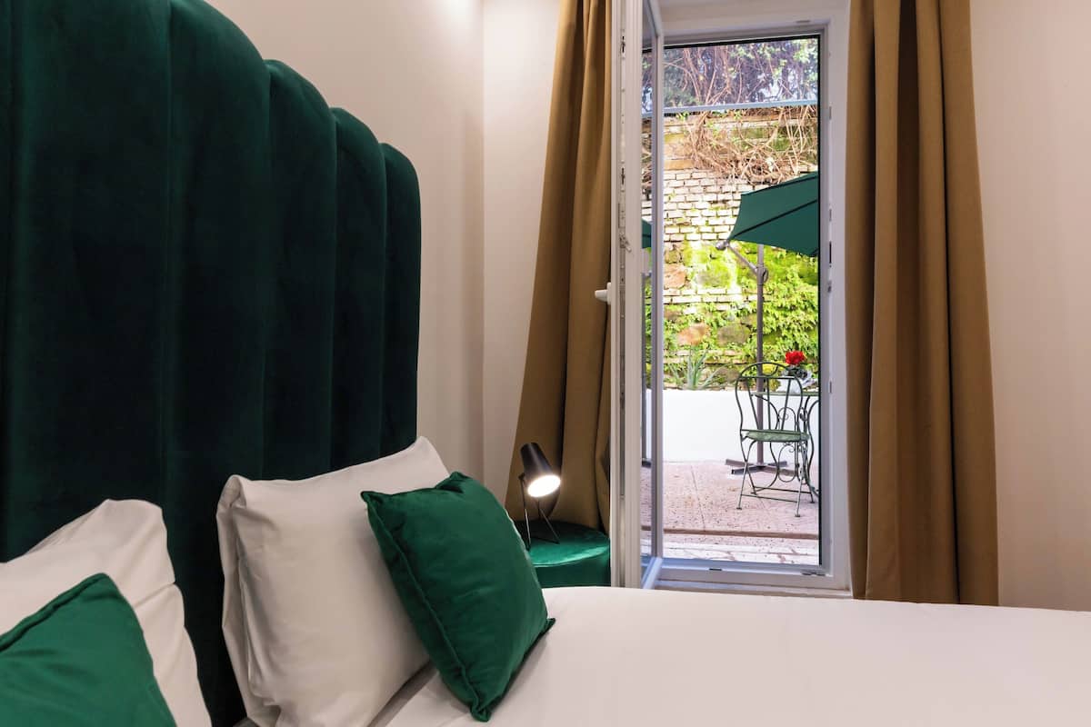 A bedroom with a bed, green pillows, a nightstand, and a window with curtains.
