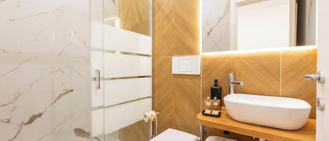A modern bathroom with a glass shower enclosure, a white sink, and a wooden vanity.