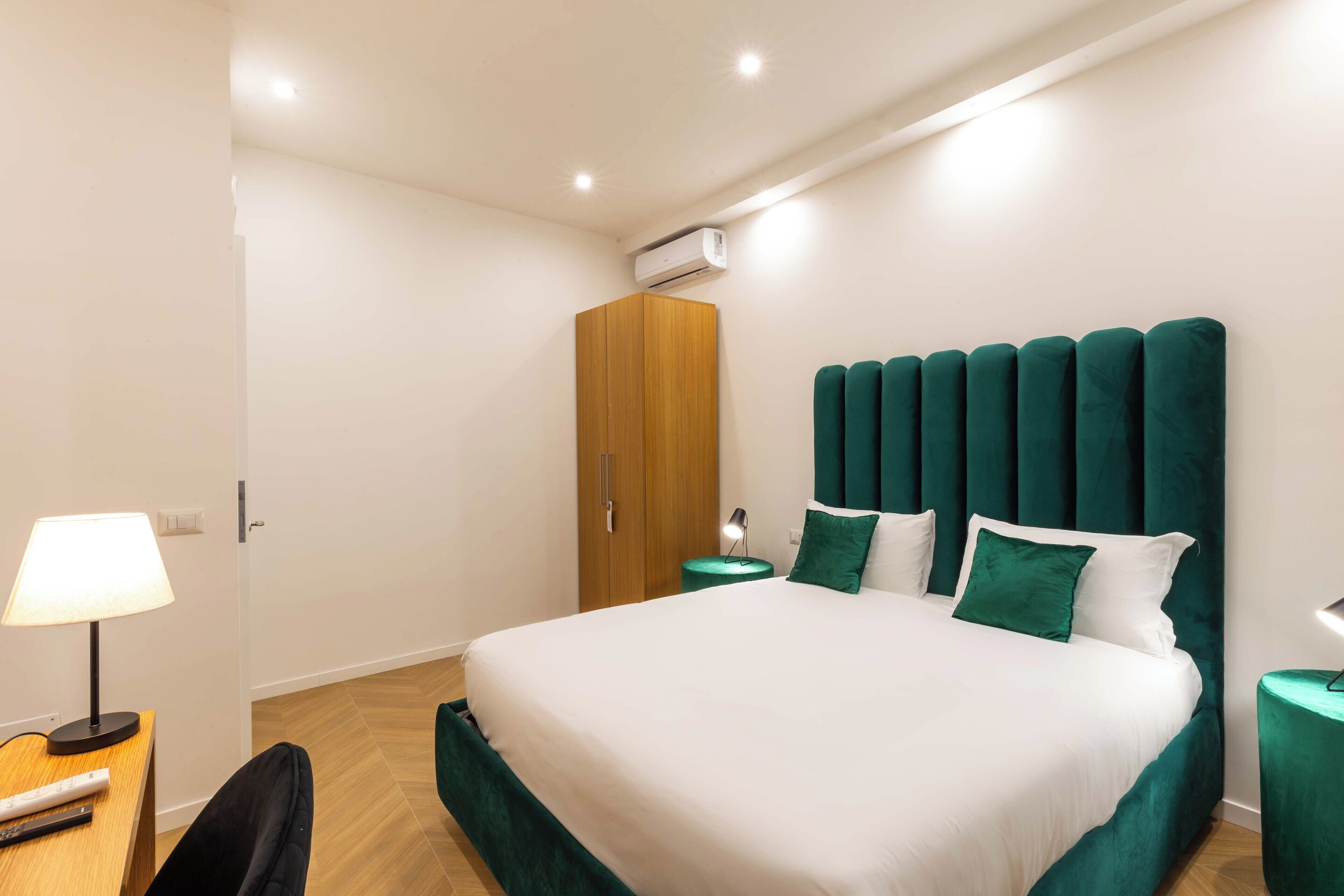 Une chambre moderne avec un grand lit, une armoire en bois et un mur d’accent vert.