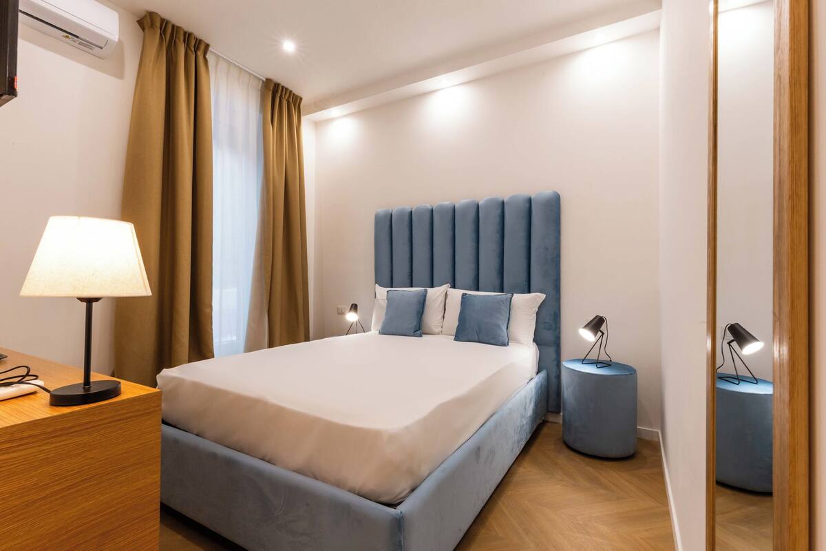A neatly arranged hotel room with a large bed, bedside lamps, and a wooden nightstand.