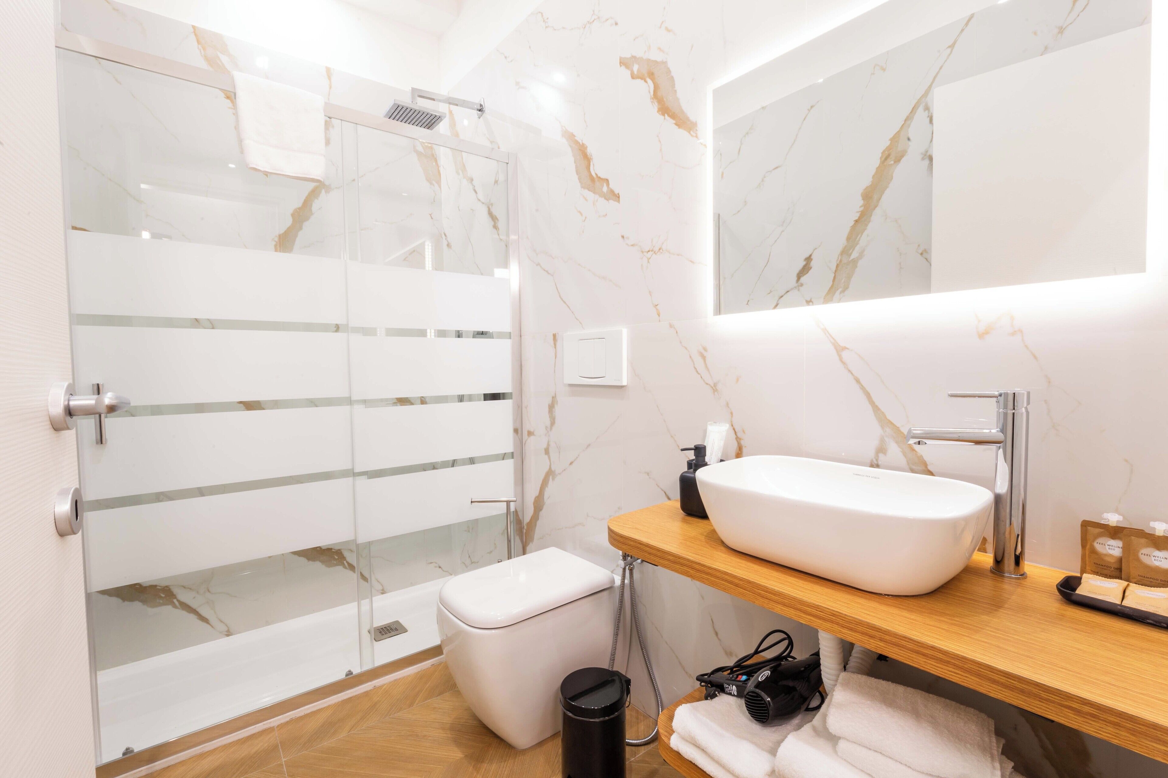 A modern bathroom with a glass shower enclosure, a white sink, and a wooden vanity.