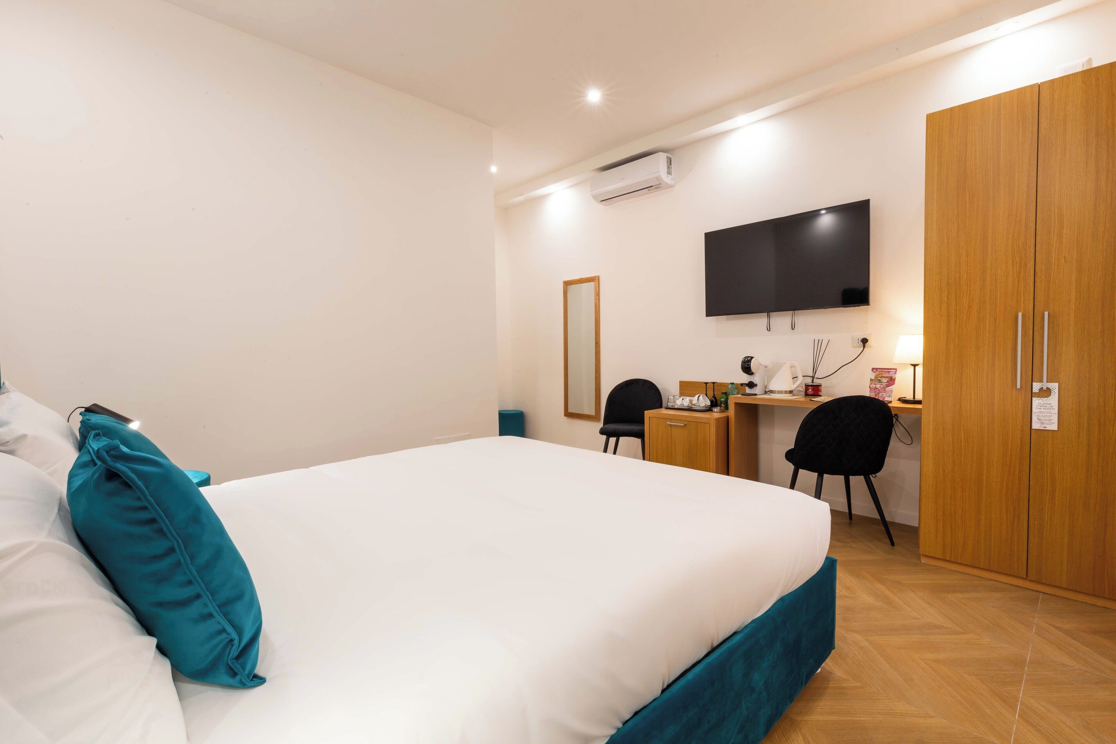 Habitación de hotel con una cama grande, un escritorio con computadora, televisión y armario.