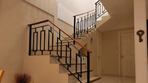 Una escalera de diseño moderno, con barandilla de metal negro y escalones de madera.