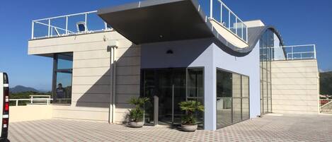 A modern building with a flat roof, large windows, and a covered entrance.