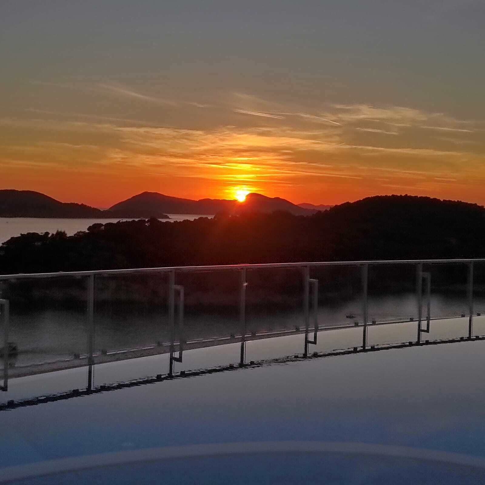 A sunset over a mountainous landscape with a clear sky.