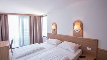 Habitación de hotel con cama doble, dos lámparas de noche, un escritorio y una silla.