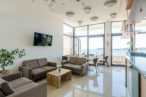 A modern hotel lobby with sofas, a coffee table, a TV, and a balcony with a view. - Villa Paradiso (Dubrovnik)