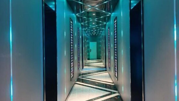 Un pasillo con superficies reflectantes e iluminación geométrica.