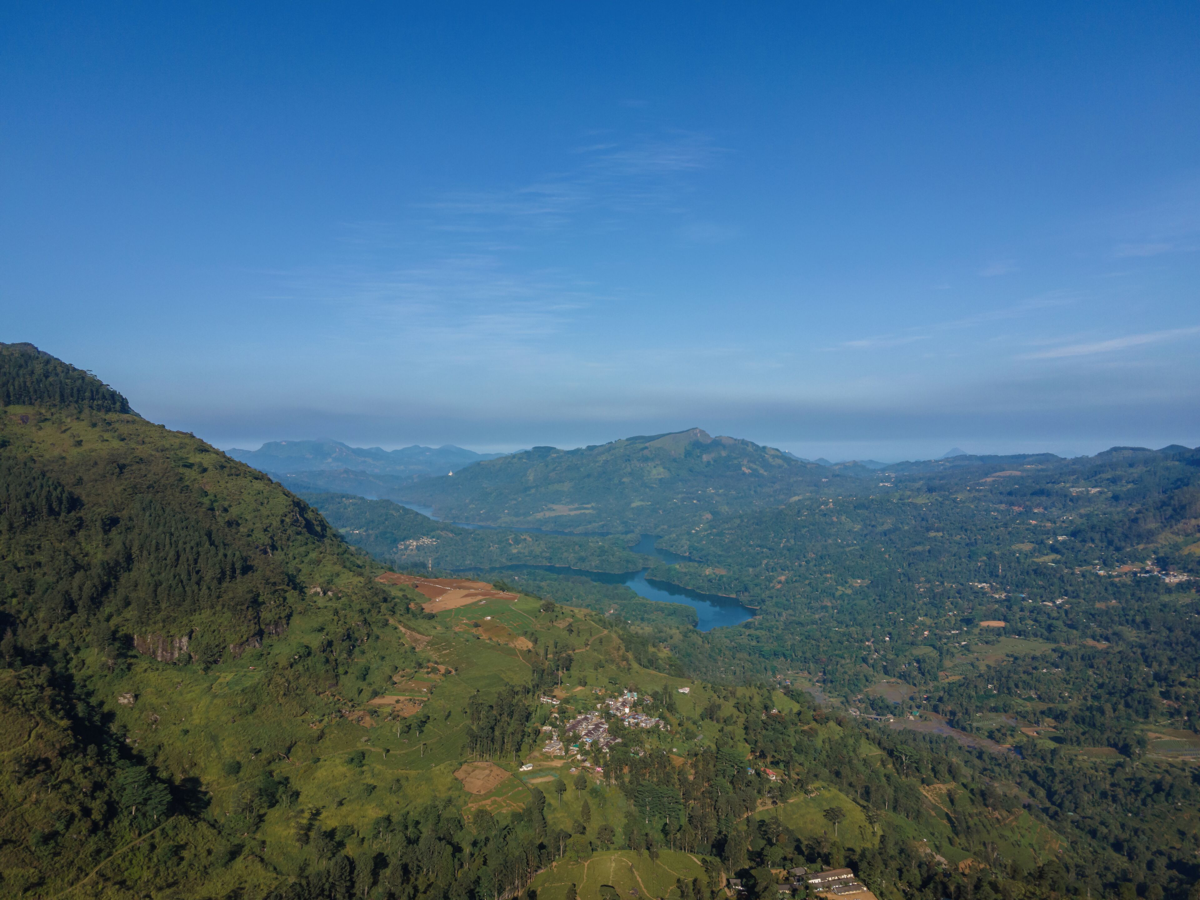 Eine gebirgige Landschaft mit einem See und verstreuten Gebäuden.
