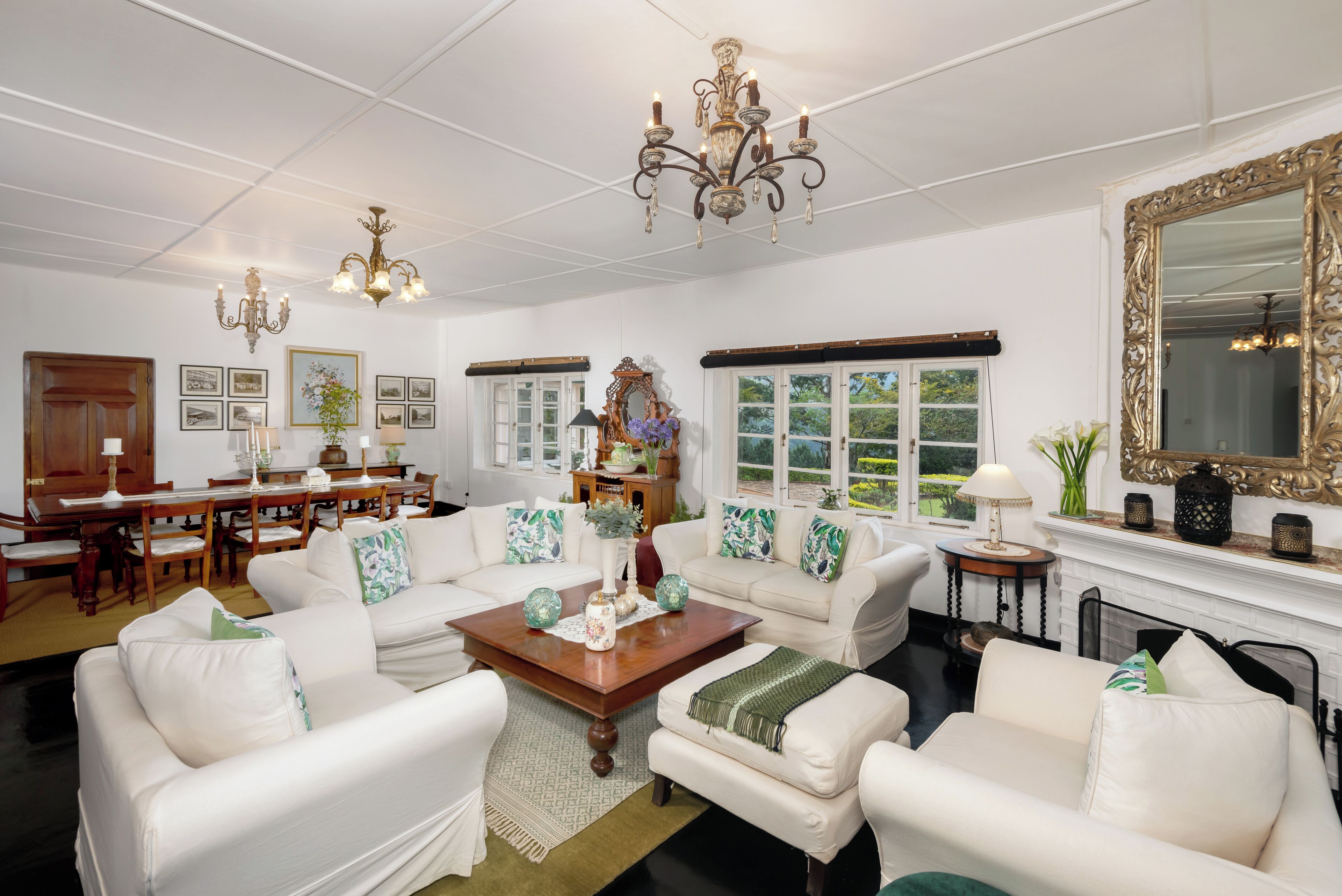 A spacious living room with white furniture, a wooden coffee table, and a large mirror.