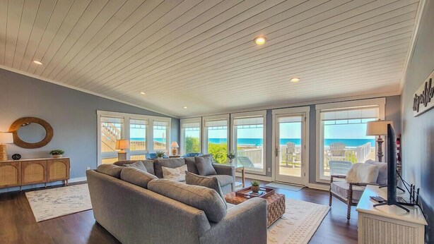 A spacious living room with a large gray sofa, a wooden cabinet, and a television. - The Sandlot - Renovated & Right on the Beach! (Topsail Beach)