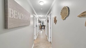 Un pasillo con un letrero que dice 'BEACH HOUSE', un comedor y conchas decorativas en las paredes.