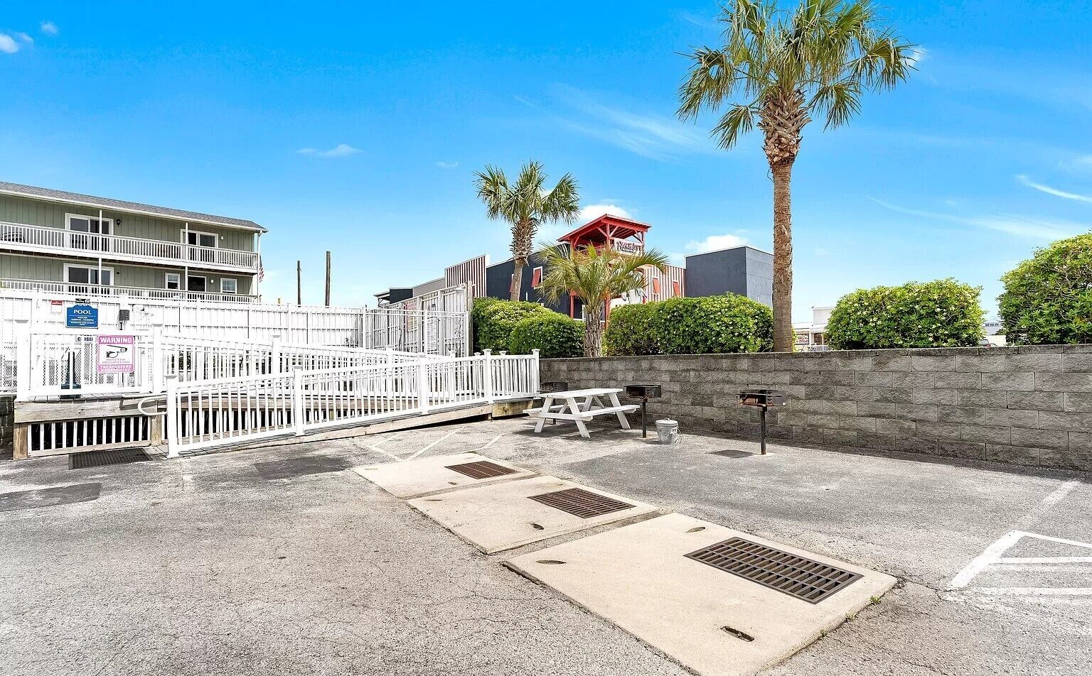A parking area with a picnic table, a pool sign, and a warning sign.