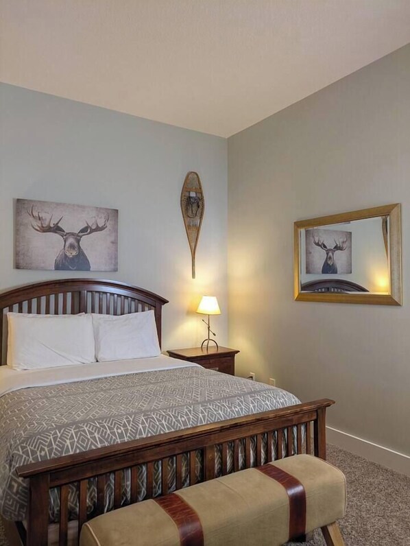 A hotel room with a bed, a nightstand, a lamp, and two framed deer pictures on the walls.