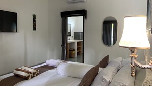 A hotel room with a bed, a TV, an air conditioning unit, a mirror, and a lamp. - Relax Villas Gili Air (Gili Air)