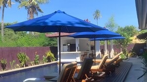 A poolside area with lounge chairs and a bar area under blue umbrellas. - Relax Villas Gili Air (Gili Air)