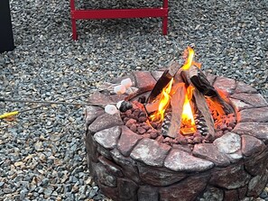 A stone fire pit with a red metal bench in the background. - Cozy Peaks & Waters: family-friendly, kitchen, near golf, hiking & fishing (Kent)