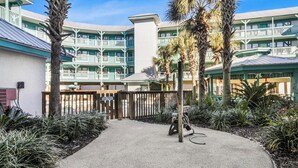 A resort with a pool area, multiple balconies, and palm trees. - 🌞Low Density | Community Pool | Sea Breeze 203🌞 (Gulf Shores)