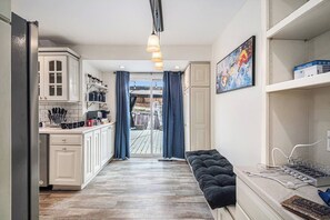 A narrow hallway with a kitchen on one side, a bench with a power strip, and a door leading to an outdoor area. - A Touch of Luxury - Arcade, 5 TVs, Bounce House, Coffee Bar (Omaha)