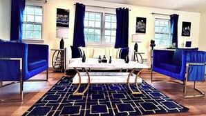 Een kamer met een witte bank, een blauwe bank, een bijzettafeltje en een kamerbreed tapijt met een patroon.