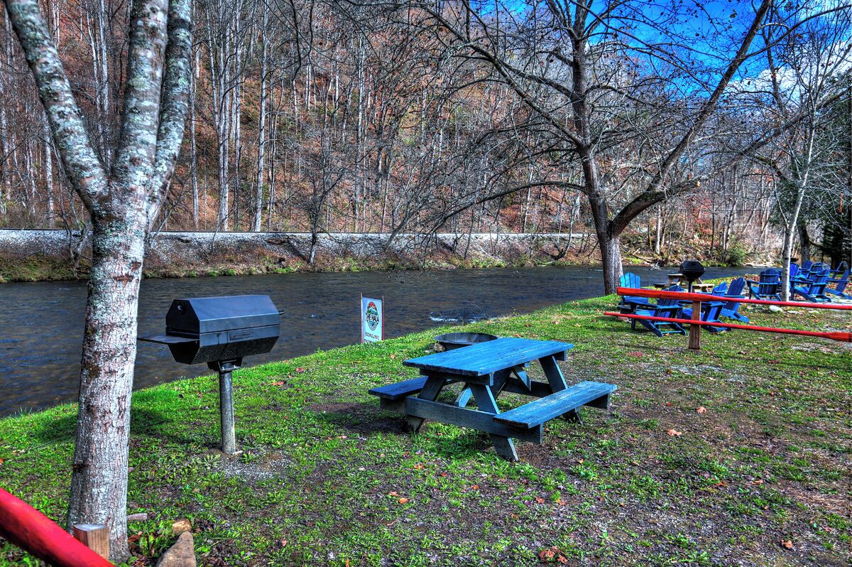 Ein Picknickplatz mit Grill und Bänken am Flussufer.