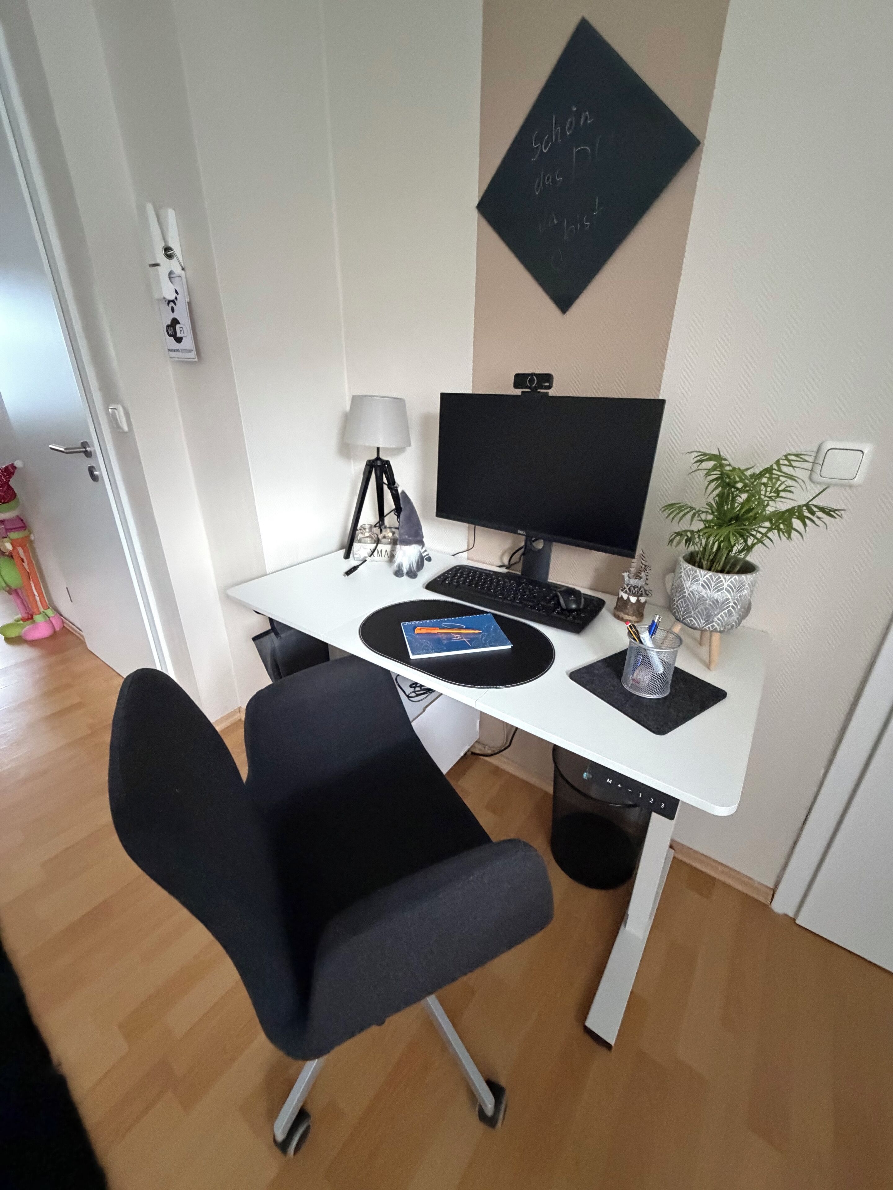 A compact office space with a desk, computer, chair, lamp, and decorative items.