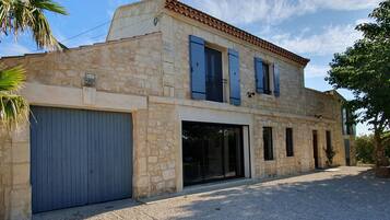 A two-story stone building with a garage, large windows, and a tiled roof.