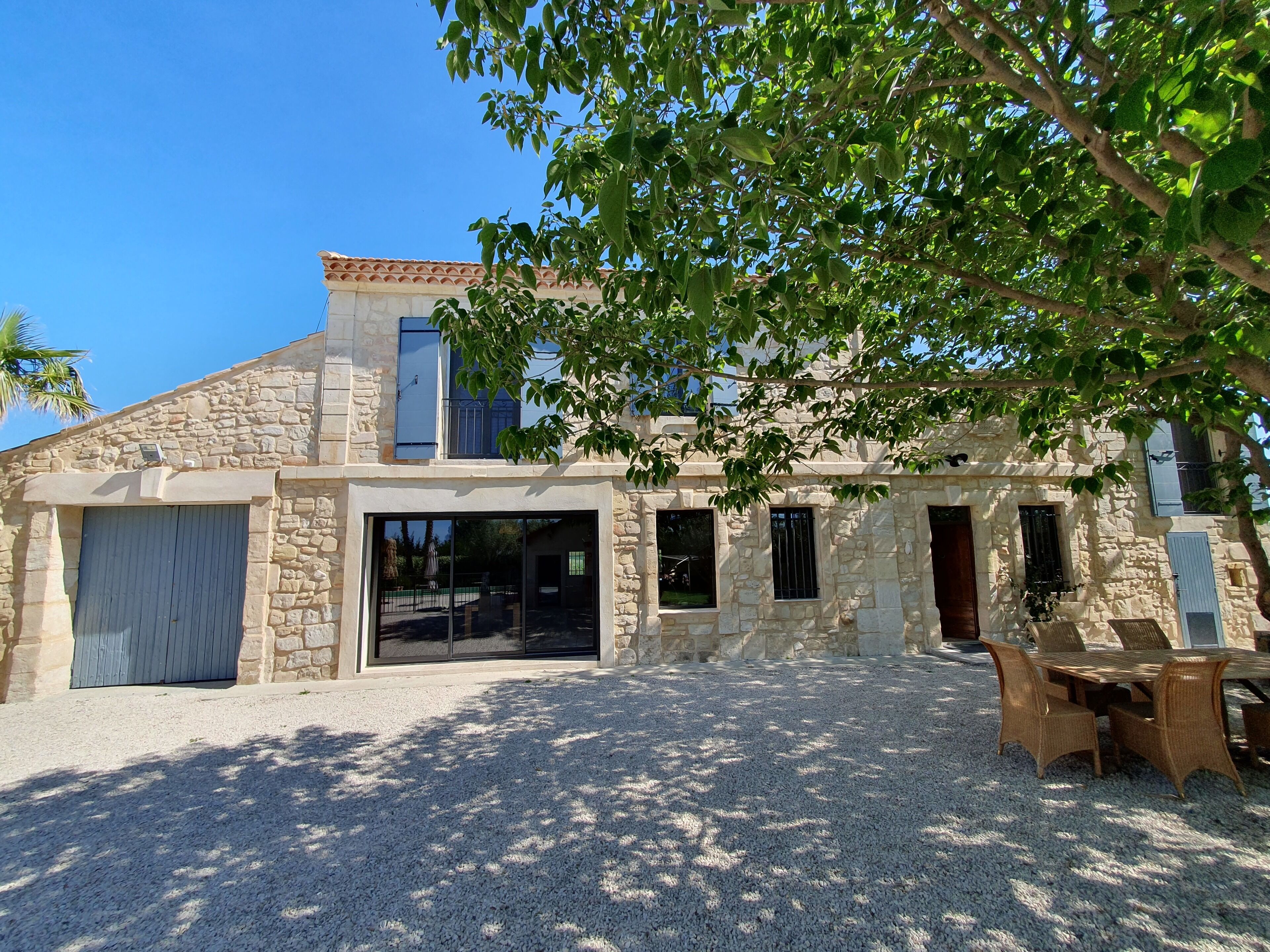 A stone building with a large sliding glass door, a gravel patio, and outdoor furniture.