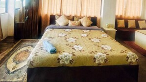 A hotel room with a large bed, a wardrobe, a desk, and a hanging light fixture. - Monratino The Snow roost (Darjeeling)