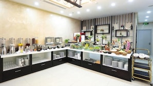 A buffet setup with various food items and beverages, a coffee station, and a decorative wall with shelves and plants. - Dung Nam Hotel (Da Nang)