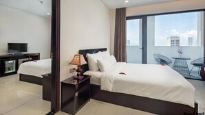 A hotel room with a bed, a TV, a lamp, a small table, and a balcony with chairs. - Dung Nam Hotel (Da Nang)