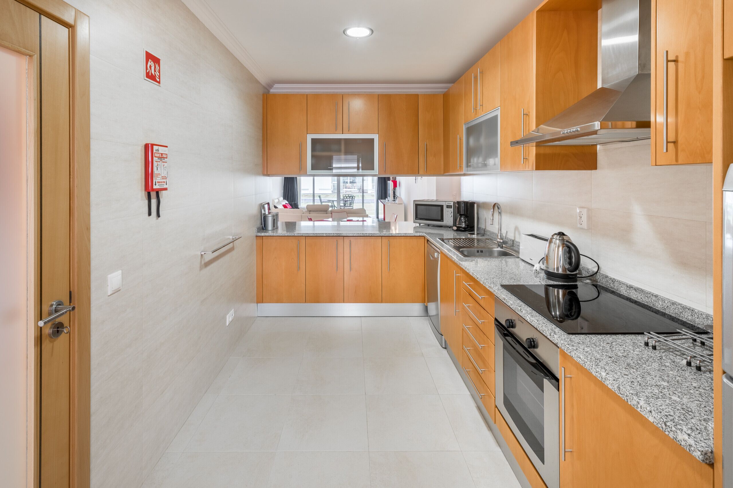 Een moderne keuken met houten kastjes, een roestvrijstalen afzuigkap, een magnetron en een waterkoker op het aanrecht.