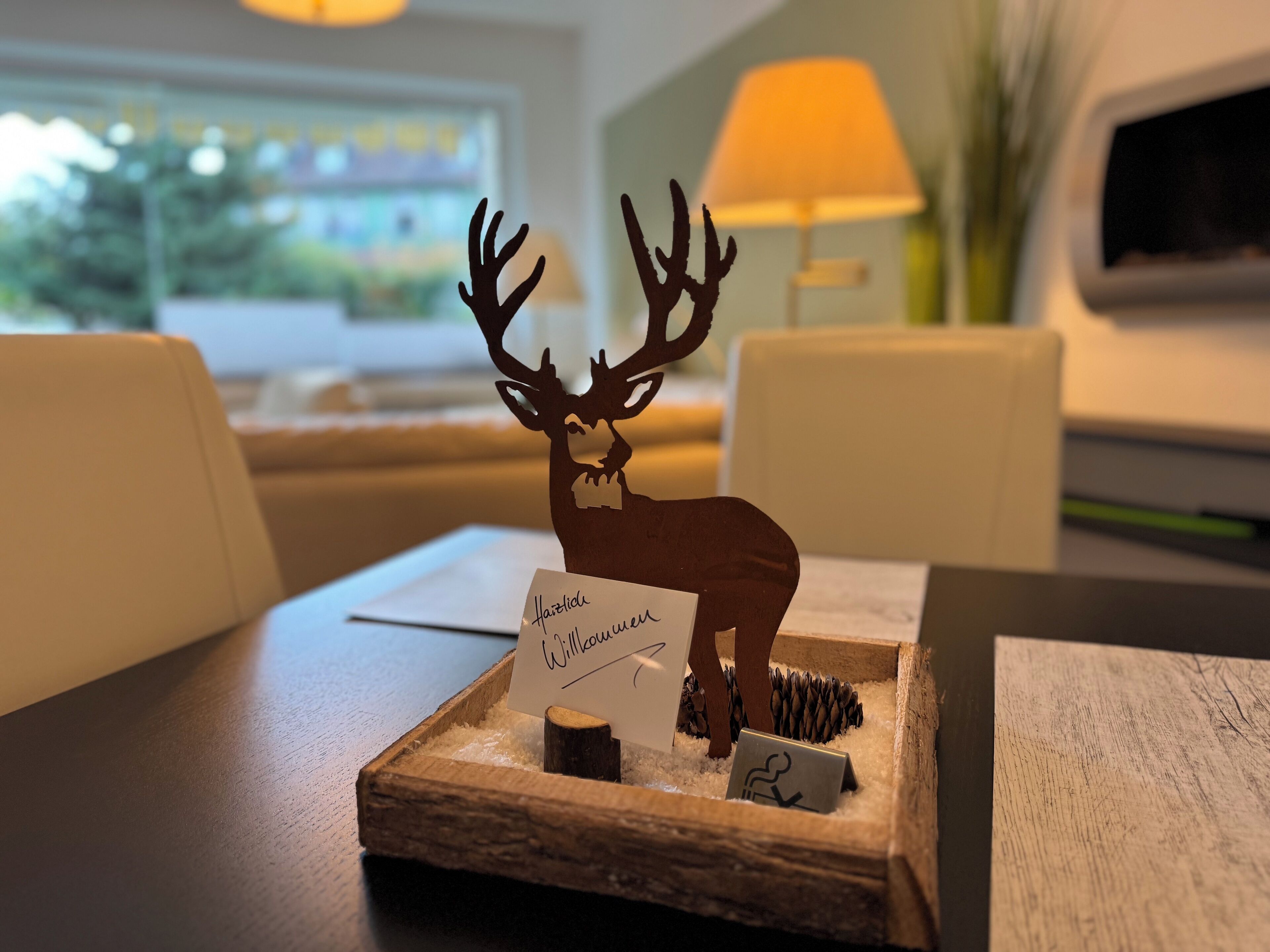 A wooden tray with a deer figurine, a name card, and a small sign.