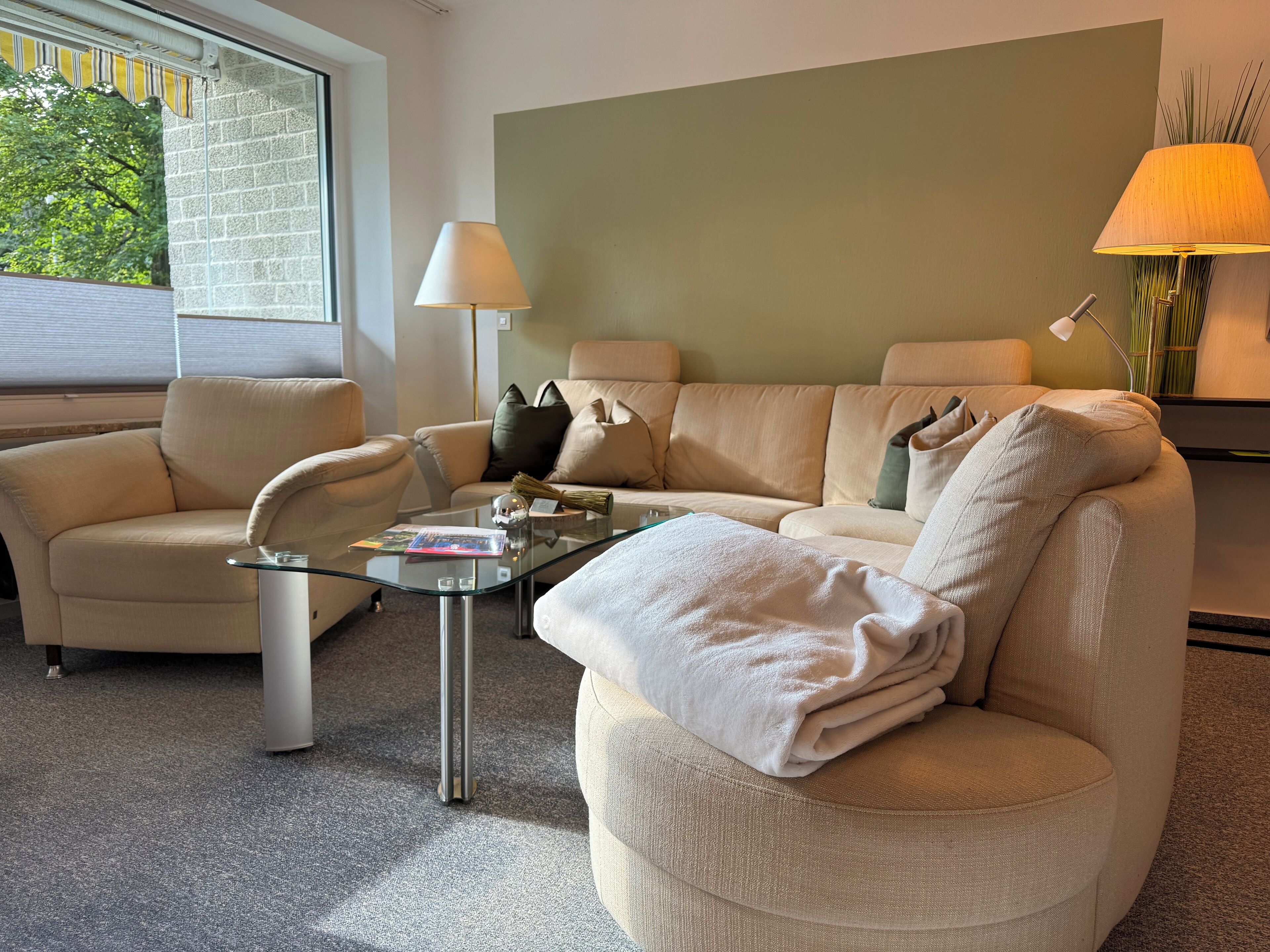 A modern living room with a beige sofa, a glass coffee table, and two lamps.