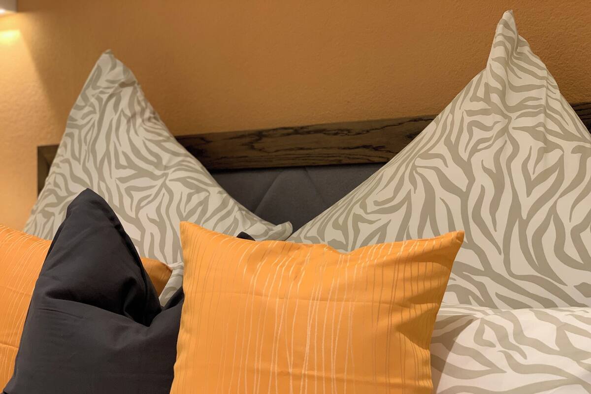 A bed with multiple pillows, including a zebra-patterned one and a striped one.