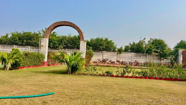 A grassy area with a brick archway, a concrete wall, and various plants.