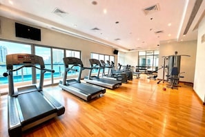 A gym with treadmills, weight machines, and a view of a body of water.