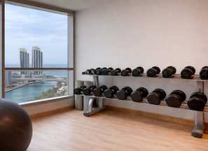 A gym with a view of a cityscape, a rack of dumbbells, and a yoga ball.
