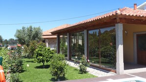Ein modernes Haus mit Ziegeldach, großen Glasfenstern und einem gepflegten Garten mit verschiedenen Pflanzen und Blumen.